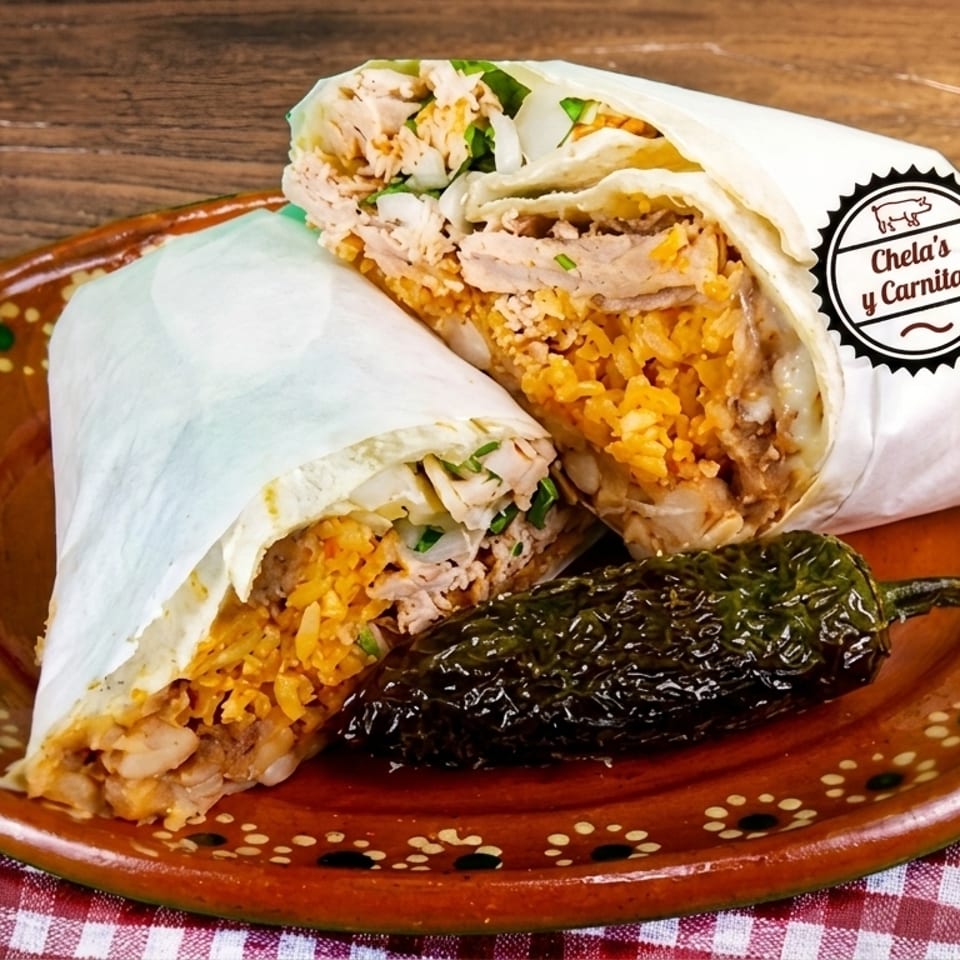 Two Chela's y Carnitas burritos, cut in half, with a roasted jalapeño on a decorative plate.